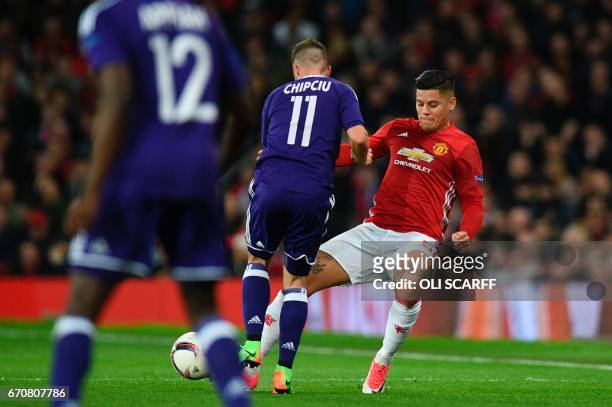 Manchester United's Argentinian defender Marcos Rojo takes a knock to his knee in a challenge with Anderlecht's Romanian midfielder Alexandru Chipciu...