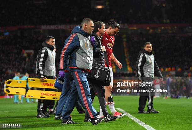 An injured Zlatan Ibrahimovic of Manchester United is given assistance during the UEFA Europa League quarter final second leg match between...