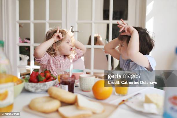 a brother and a sister having their breakfast - haciendo burla fotografías e imágenes de stock