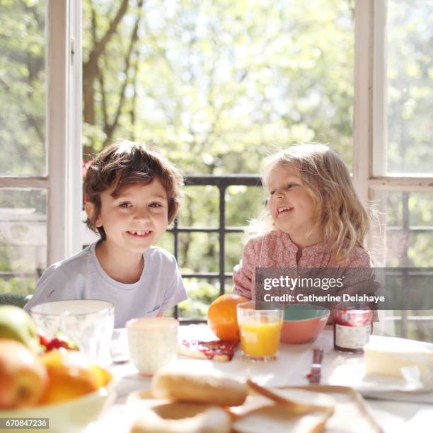 a brother and a sister having their breakfast - fratrie stock-fotos und bilder