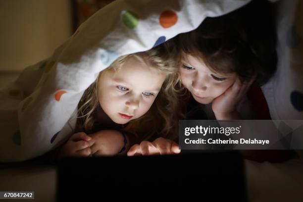 a brother and a sister looking at a tablet - intérieur de maison 個照片及圖片檔