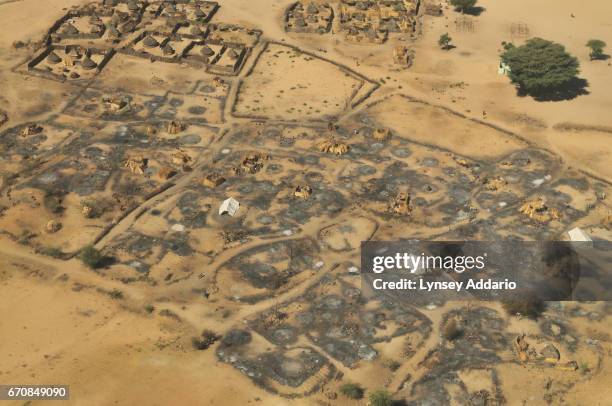 Sudanese women sit and await food and non-food items being distributed by international humanitarian organizations in the village of Silea, which was...