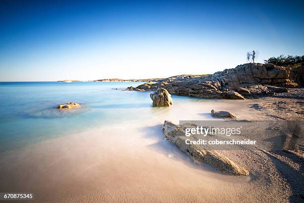 silhouette of two people standing on rocks at beach, corsica, france - corsica beach stock pictures, royalty-free photos & images