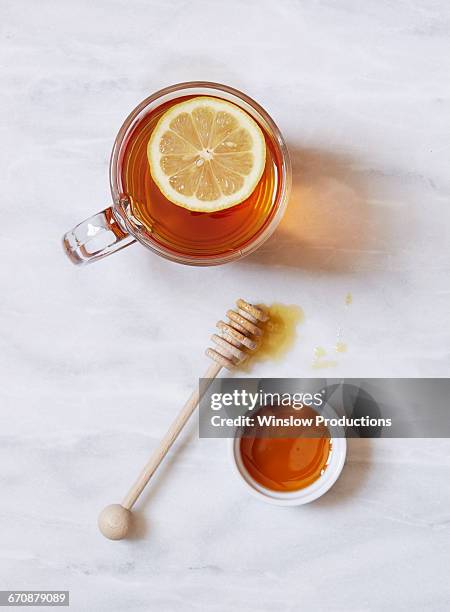 overhead view of cup of tea with lemon and bowl of honey on marble table - tea cup overhead view photos et images de collection