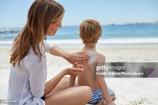 mother applying sun cream to son - applying sunscreen stock pictures, royalty-free photos & images