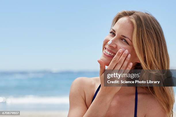 woman applying sun cream on beach - sunscreen imagens e fotografias de stock