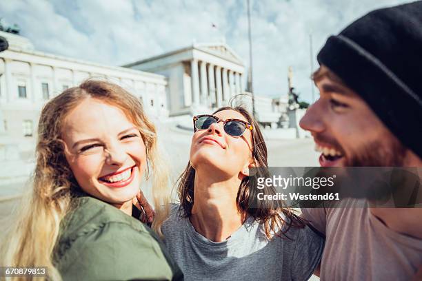 austria, vienna, three friends having fun in front of the parliament building - freundschaft stock-fotos und bilder