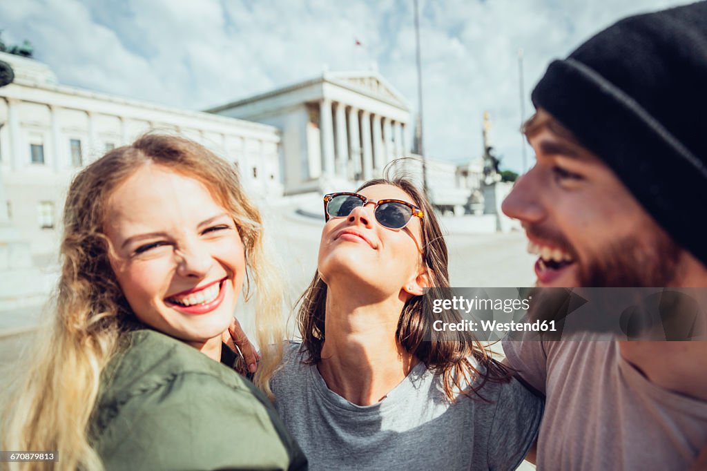 Austria, Vienna, three friends having fun in front of the parliament building