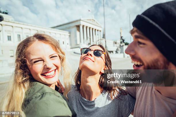 austria, vienna, three friends having fun in front of the parliament building - tourist group foto e immagini stock