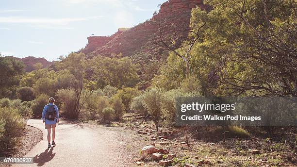 australia, outback, northern territory, red centre, west macdonnel ranges, kings canyon, woman walking down mountain road - kings canyon australia stockfoto's en -beelden