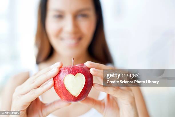 young woman holding apple with heart - apple heart stock pictures, royalty-free photos & images