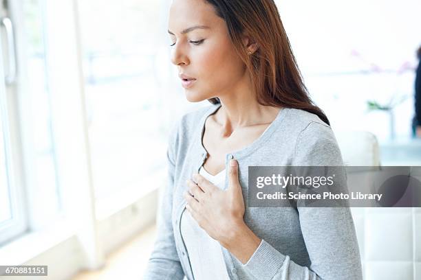 young woman with hand on chest - panic attack stock-fotos und bilder