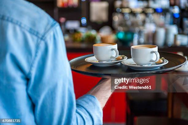 waiter carrying tray with cappuccino cups in a cafe - empregado de mesa imagens e fotografias de stock