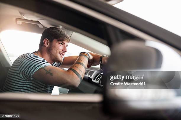 smiling young man in car - smiling controluce foto e immagini stock