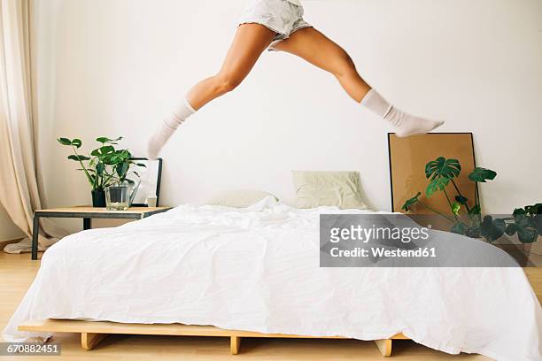 legs of young woman jumping on bed - legs in stockings stock-fotos und bilder