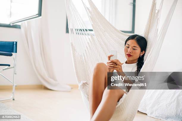 young woman sitting in hammock using cell phone - weave hammock stock pictures, royalty-free photos & images