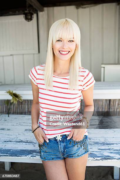 portrait of smiling blond woman wearing striped t-shirt and hot pants - short hair photos et images de collection