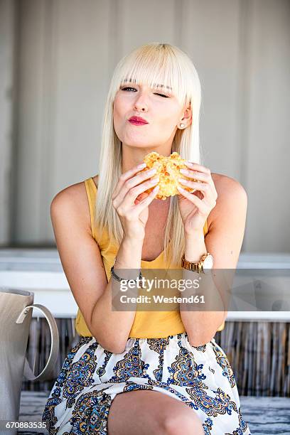 portrait of blond woman eating a bread roll - brot mund stock-fotos und bilder