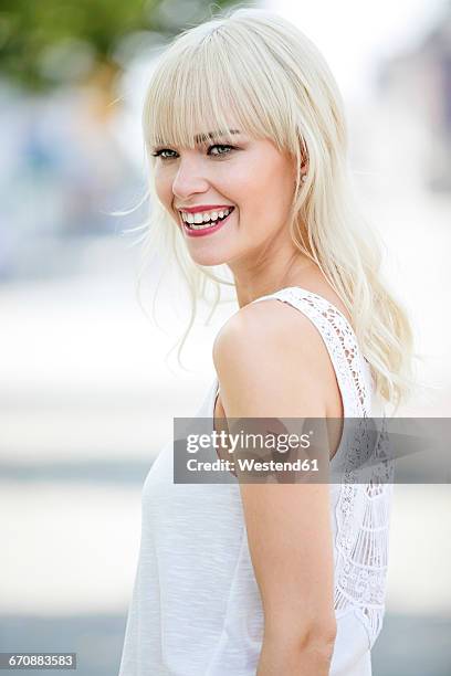 portrait of smiling blond woman wearing white top - frangia foto e immagini stock