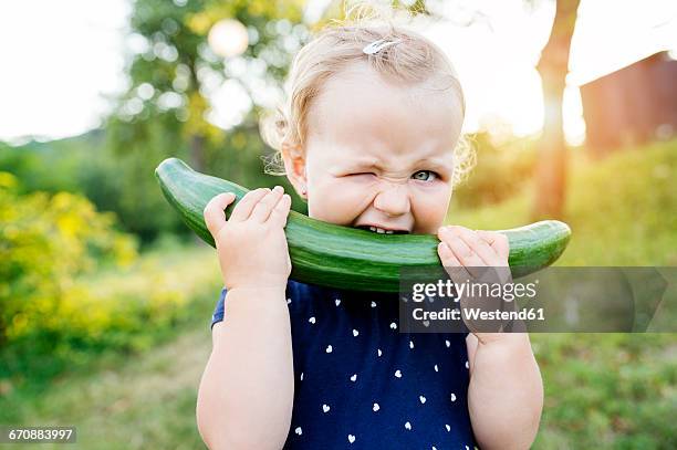 portrait of little girl biting in cucumber - mordre photos et images de collection