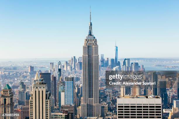 new york skyline on a sunny day with clear blue sky - empire state building stockfoto's en -beelden