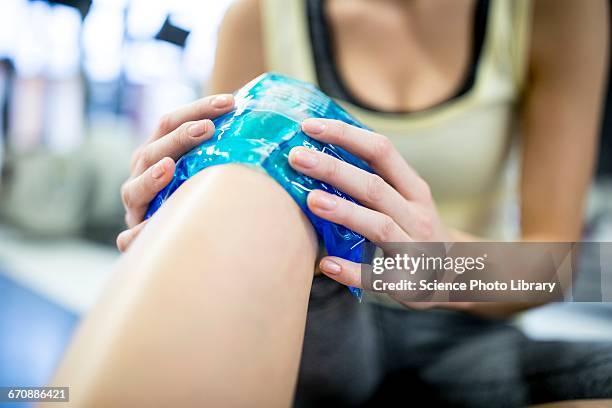 young woman holding ice pack on knee - ijszak stockfoto's en -beelden