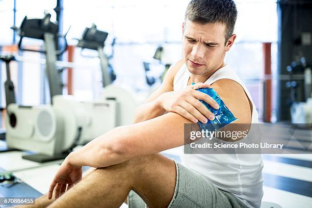 young man holding ice pack on shoulder - compresse stock-fotos und bilder