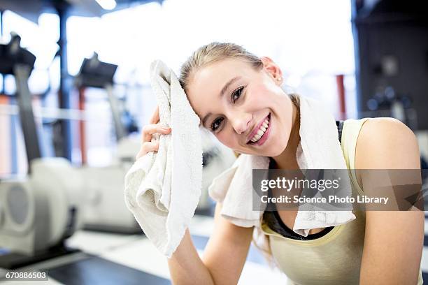 young woman wiping her sweat with towel - leisure facilities stock pictures, royalty-free photos & images