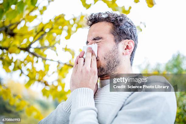 young man sneezing - allergie foto e immagini stock