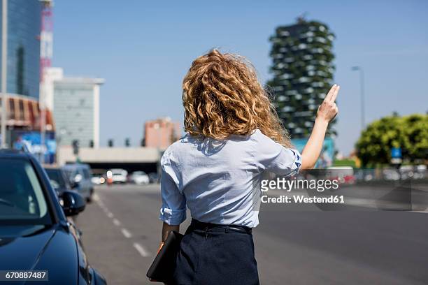 businesswoman at the roadside hailing a taxi - hail foto e immagini stock