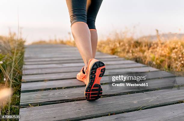 spain, aviles, young athlete woman running along a coastal path at sunset - female soles stockfoto's en -beelden