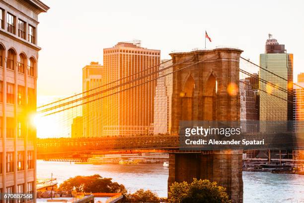sunset over brooklyn bridge and skyline of manhattan financial district in downtown, new york city, ny, united states - brooklyn new york stock pictures, royalty-free photos & images