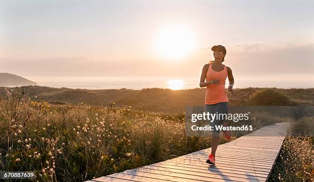 spain, aviles, young athlete woman running along a coastal path at sunset - woman outdoors fotografías e im�ágenes de stock