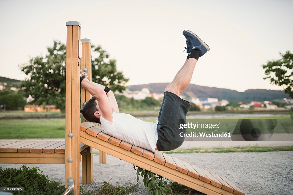 Young man doing sit-ups in a park, outdoors