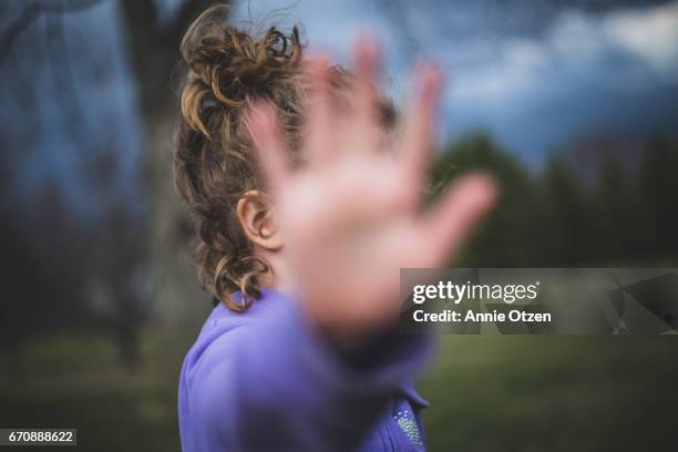 girl holding hand up to camera - verbergen stockfoto's en -beelden
