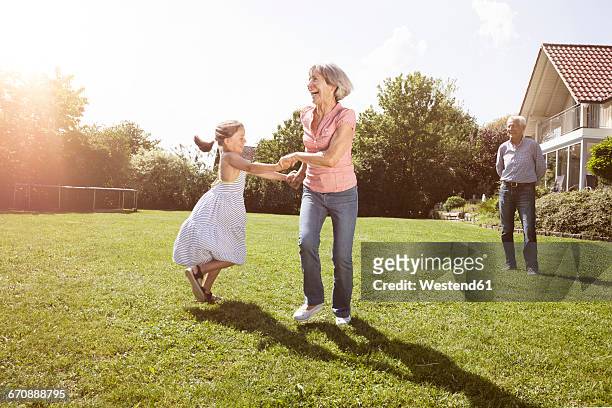playful grandmother with granddaughter in garden - three people dancing stock pictures, royalty-free photos & images