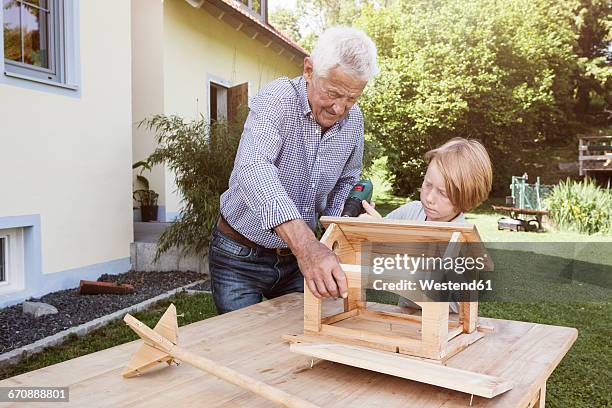 grandfather and grandson building up a birdhouse - bird house imagens e fotografias de stock