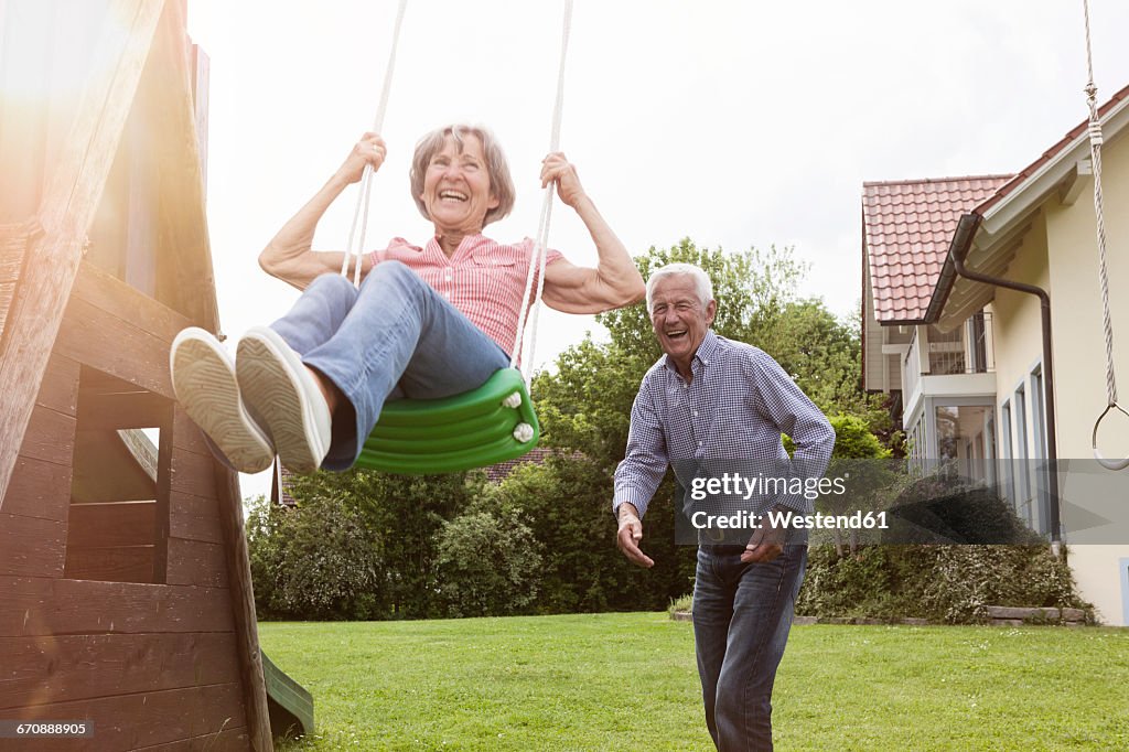 Playful senior couple with swing in garden