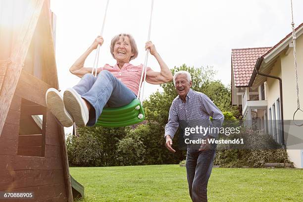 playful senior couple with swing in garden - couple swinging stock pictures, royalty-free photos & images