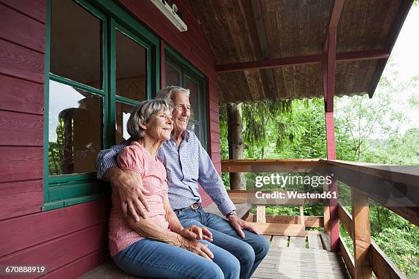 happy senior couple relaxing on porch of log cabin - alpendre imagens e fotografias de stock