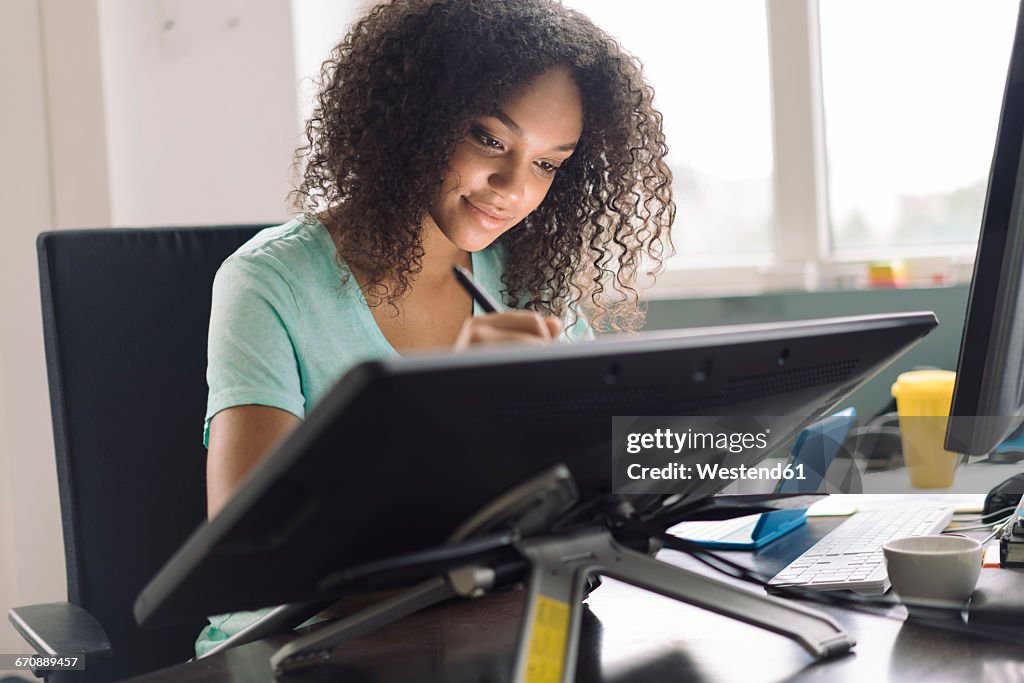 Young female designer drawing on digital tablet