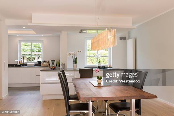modern dining area with open plan kitchen in the background - dining hall stock pictures, royalty-free photos & images