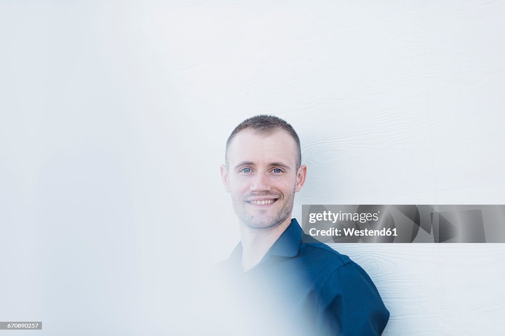 Portrait of smiling businessman in front of white wall