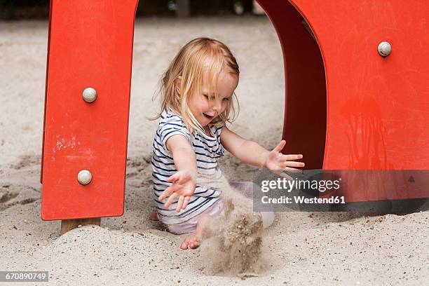 blond little girl in sandbox on playground - sandbox stock-fotos und bilder