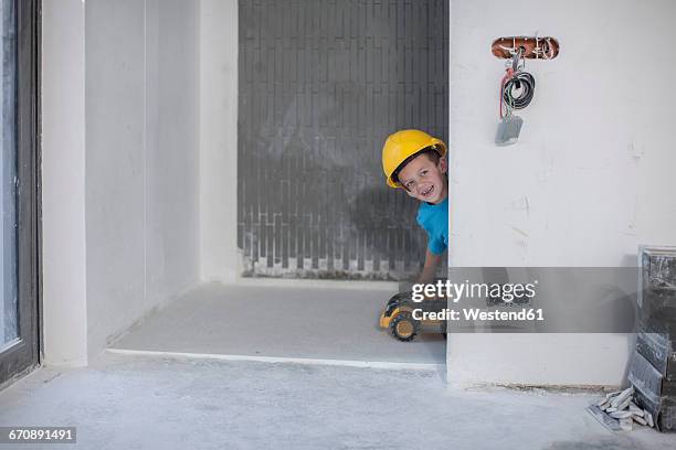 happy boy with hard hat playing on construction site - boy in hard hat photos et images de collection