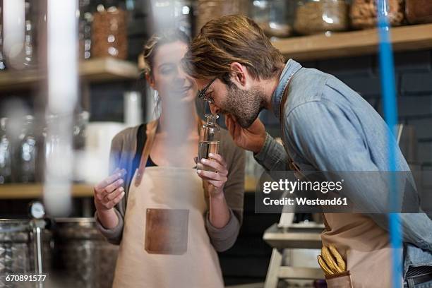 colleagues smelling at liquid in distillery - distillery stock pictures, royalty-free photos & images