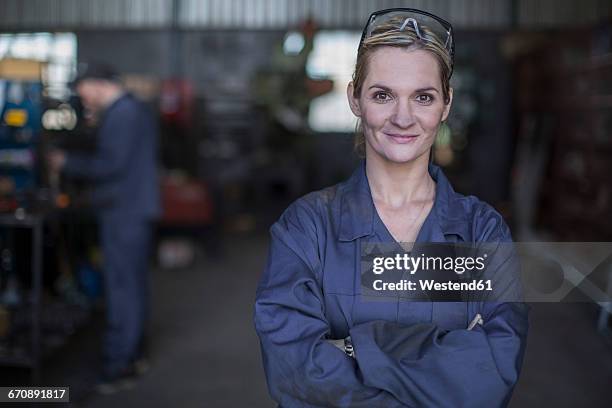 portrait of confident female mechanic in workshop - overall stock-fotos und bilder