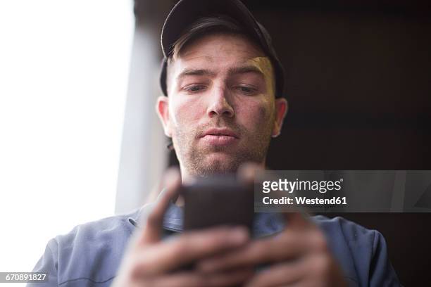 mechanic looking at cell phone - mobile phone reading low angle stock-fotos und bilder