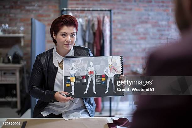 woman showing fashion sketchbook to man - fashion designer stockfoto's en -beelden