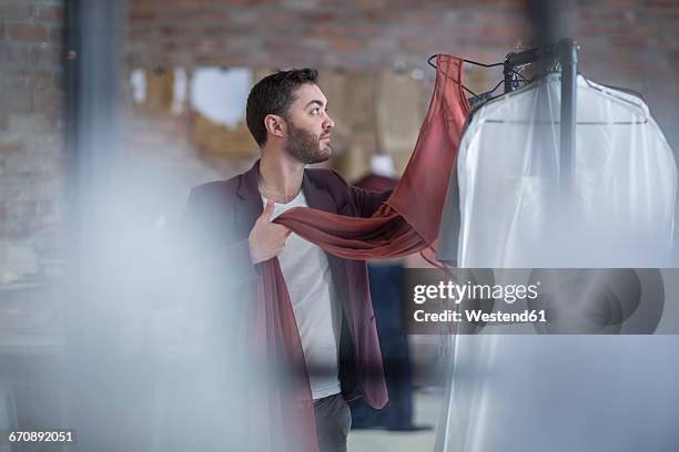 man looking at dress in boutique - stilista di moda foto e immagini stock